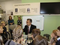 Дети и родители слушают лекцию у стенда геометрической оптики